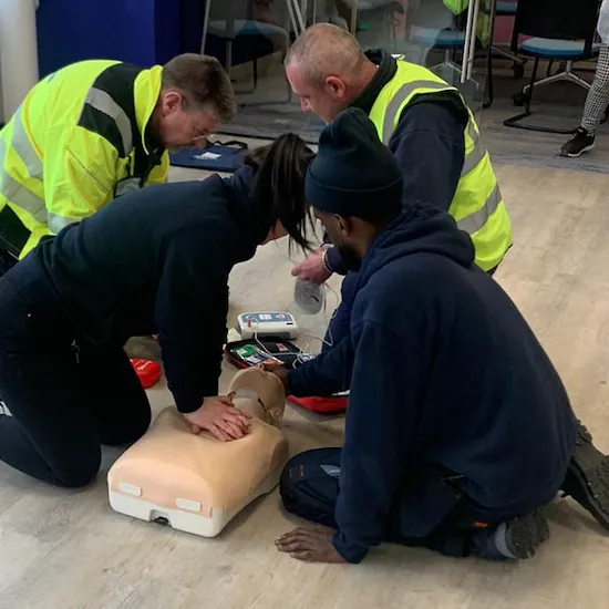 Delegates in hi-vis practising CPR on a manikin
