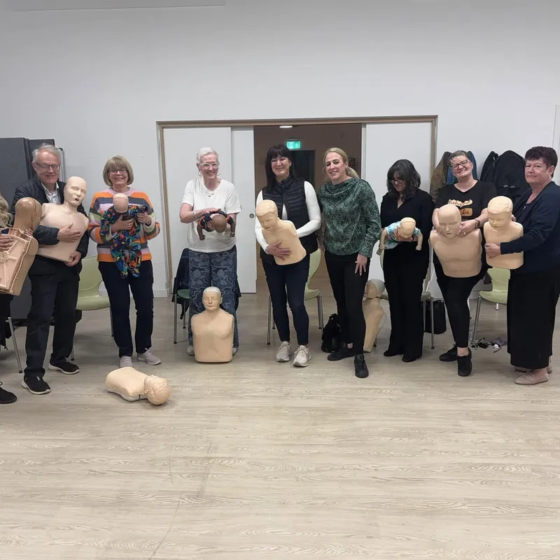 A group holding their CPR manikins after a session