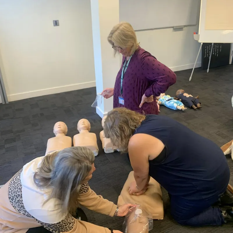 Delegates kneeling to practise CPR on adult manikins