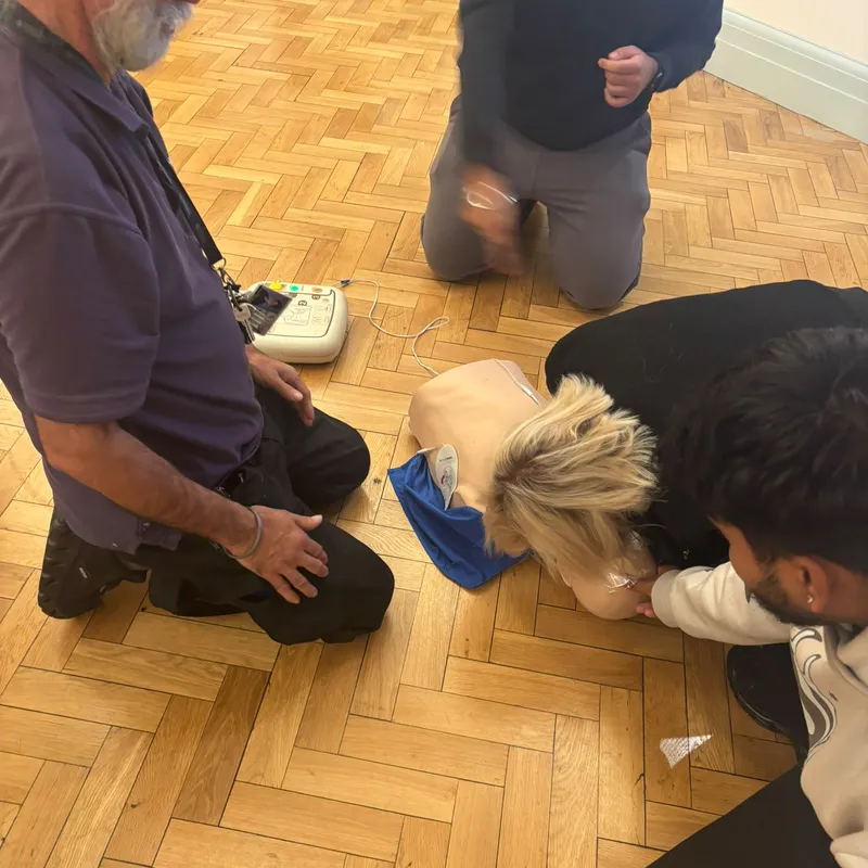 Checking a CPR manikin for breathing, with the AED trainer alongside