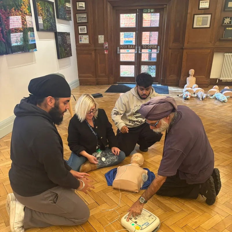 Using an AED trainer beside a CPR manikin at Villiers High School, Southall