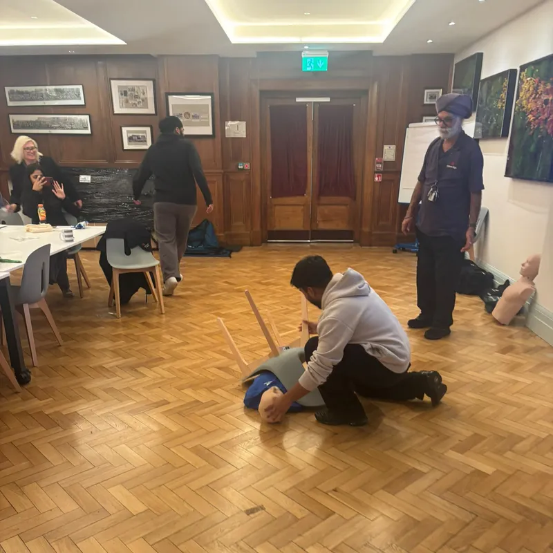 Kneeling beside a training manikin on the floor during a practical scenario