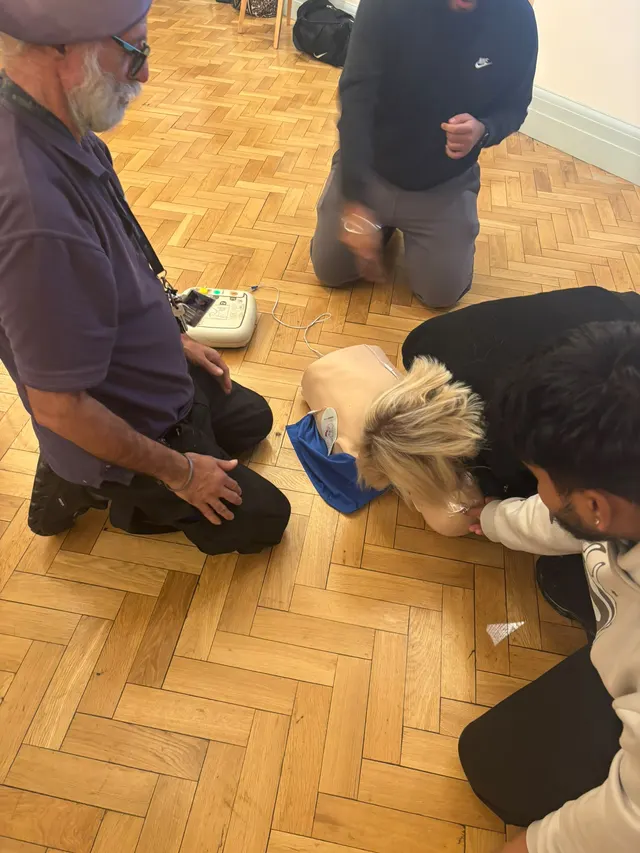Checking a CPR manikin for breathing, with the AED trainer alongside