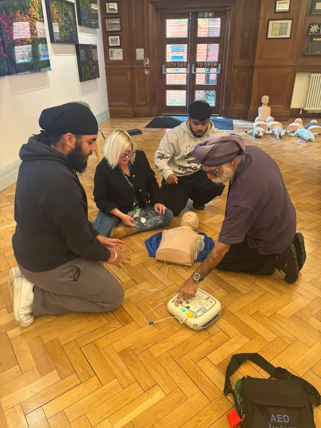 Using an AED trainer beside a CPR manikin at Villiers High School