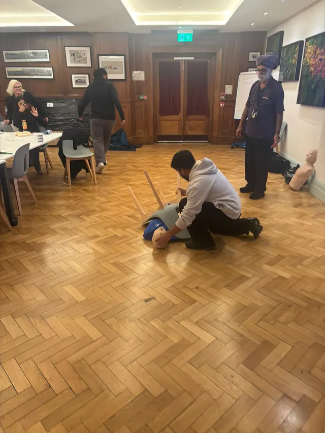 Kneeling beside a training manikin on the floor during a practical scenario